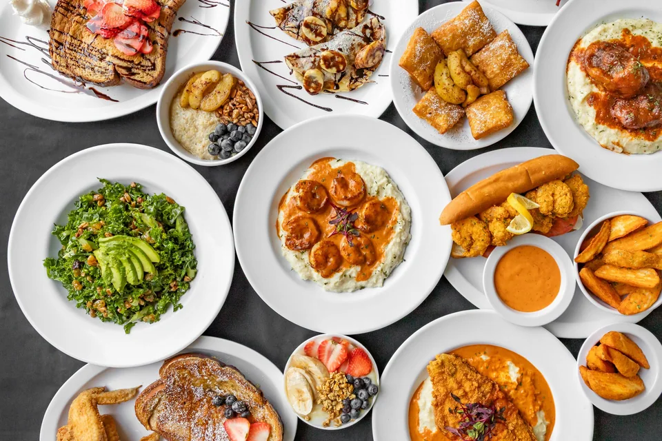 An overhead spread of brunch dishes including avocado toast, eggs and French toast from French Toast in Atlanta