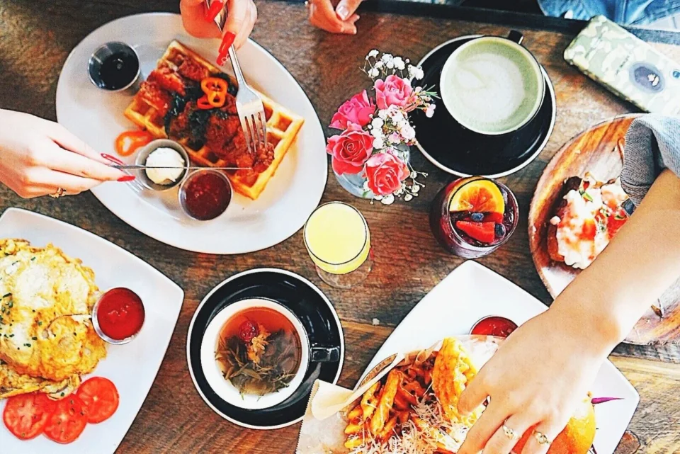 An overhead brunch spread with waffles, eggs, coffee and colorful drinks at Met Her At A Bar in Los Angeles